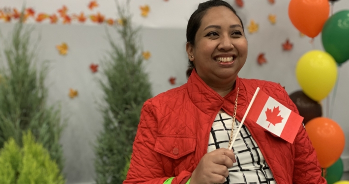 Claire Amisco wears red jacket holding Canadian flag